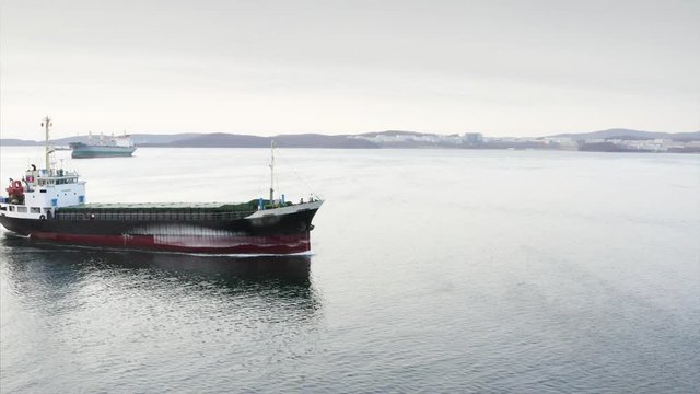 Aerial zooming in view of trading ship floating along the strait in Vladivostok
