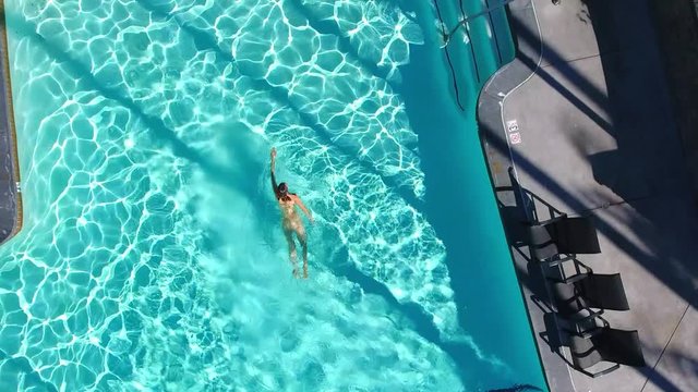 Top view of a naked girl swims in the swimming pool.