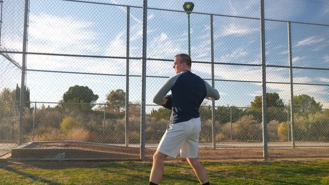 An athlete baseball player catching and throwing a ball to a teammate in slow motion on a grass park field during spring training.