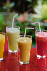 Healthy Fresh Different Smoothie Cocktail Beverage. Green and Orange Assorted Detox Shake Drink for Breakfast Diet Nutrition. Organic Summer Sweet Fruit Juice Blend on Red Rustic Background
