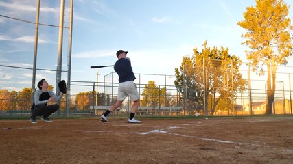 A young baseball player hits a pop fly ball and then ducks to avoid getting hit on the head in slow motion over home plate. - Powered by Adobe