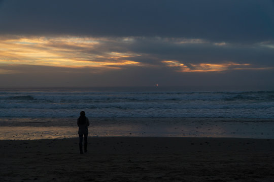 Woman taking pictures of the sunset on the Oregon coast