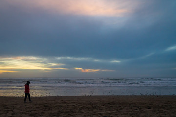 Fototapeta na wymiar Woman waling on the beach at sunset on the Oregon coast