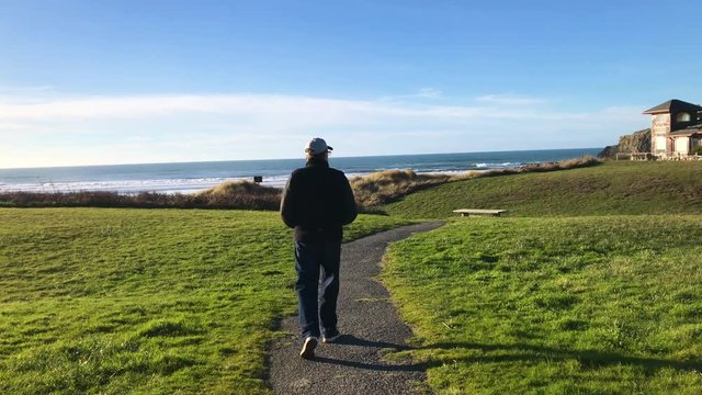 Middle aged male in winter clothing walking down to Devil's Kitchen, part of Bandon Beach State Park in Southern Oregon