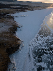 Aerial shot of Olkhon island on sunset in winter. Frozen lake Baikal. Ice and snow. Abraham Lake,...
