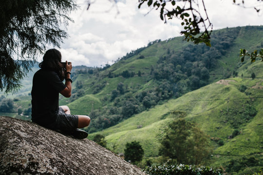 Young male photographer taking pictures of beautiful valley in Malaysia Cameron Highlands