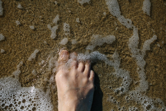 Foot in sea water on the beach