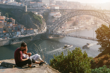 A gay couple traveling and enjoy sunset outdoor, european city view with bridge and river - obrazy, fototapety, plakaty