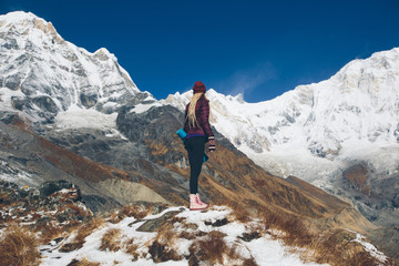 Mountain hiking, woman standing on rock with yoga mat and enjoy Annapurna mountains view