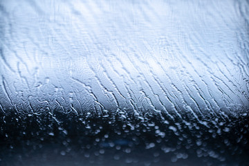 the texture of the flowing water on the glass of the car during the car wash with various highlights and shadows, bokeh