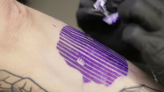 Tattoo artist fills tattoo on skin of client, macro view on the needle