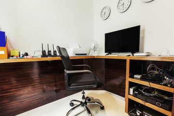 Modern study or working office room at home with chair and desk. Radio, phone, clocks with time in different countries, printer, office equipment