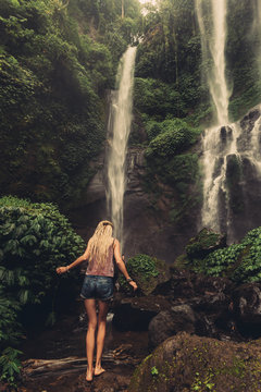 Young woman walking to jungle waterfall
