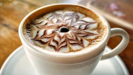 cup of coffee with cream on wooden background