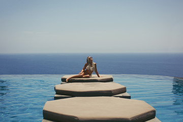 Naklejka na ściany i meble Woman enjoying in swimming pool with sea background view