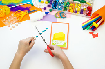 Child makes a postcard with a picture of a cake. Kid paperwork.