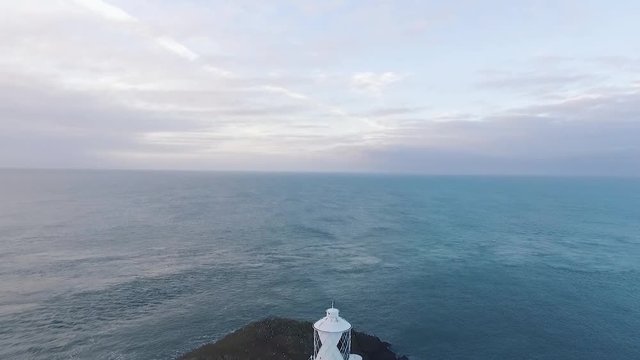 Aerial view of Strumble Head Lighthouse in the evening. Drone slow pull back reveal.