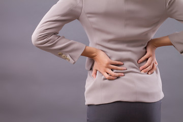 woman with back pain symptoms, office syndrome; portrait of asian woman suffering from back pain injury, girl with slipped backbone disc or herniated spinal disc injury; asian adult woman model