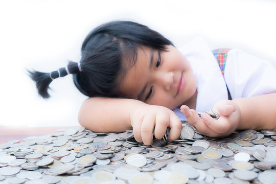 Cute little child girl hand protecting with stacked lots Coins, Portrait of beautiful happy kid lady pick up money on wooden table with white background, Planning Investment and saving concept