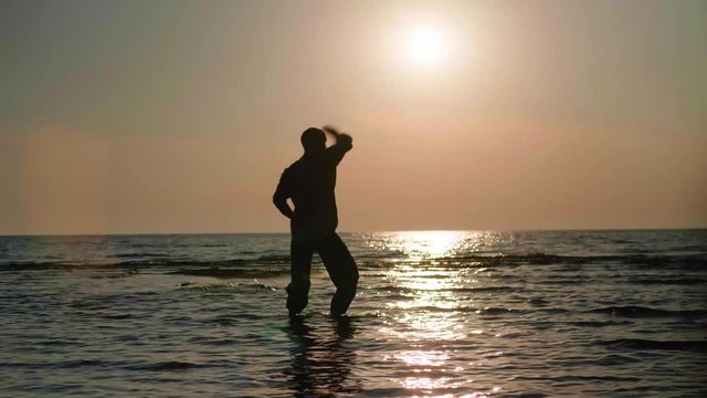 Martial artist monk practicing routine on the beach.