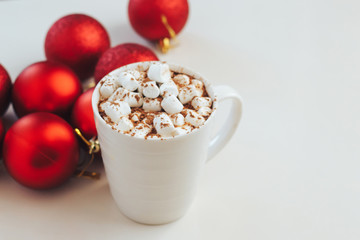 Cocoa mug with marshmallows on the background of red christmas balls