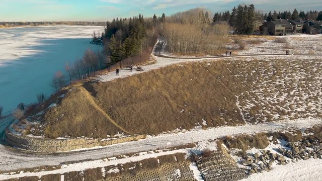 Arial Shot Of Parkway Over Frozen Lake With Bike Path And Trees