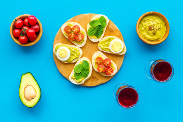 Healthy snacks. Set of toasts with vegetables like avocado, guacamole, rocket, cherry tomatoes on blue background top view