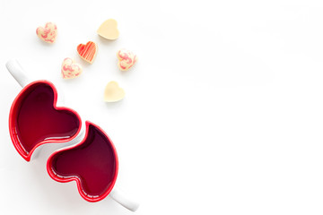 Valentine's day concept. Heart-shaped mugs and sweets on white background top view copy space