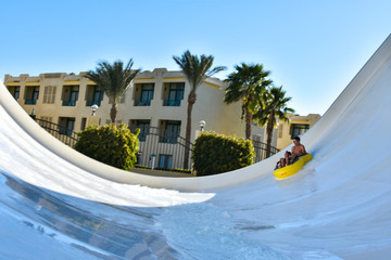 A family of dad and son ride a tubing on a fast water attraction in an aquapark