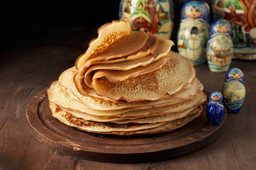 Stack of russian pancakes blini and traditional wooden dolls matrioshka