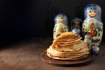Stack of russian pancakes blini and traditional wooden dolls matrioshka