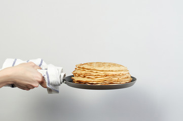 Stack of russian pancake blini in pan woman holds in hands - obrazy, fototapety, plakaty