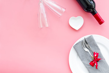 Valentine's day dinner concept. Decorated dishes, tableware, wine on pink background top view space for text
