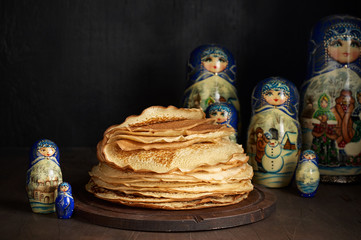 Stack of russian pancakes blini and traditional wooden dolls matrioshka