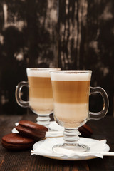 Coffee in glass on the wooden background.  A glass with cappuccino and cinnamon. 