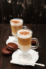 Coffee in glass on the wooden background.  A glass with cappuccino and cinnamon. 