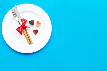 Dating on Valentine's day concept. Festive dishes, tableware on plate on blue background top view space for text