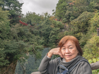Naklejka na ściany i meble Portrait photo of Senior asian women with Tianxiadiyi bridge the Great Nature bridge at Zhangjiajie National Forest Park in Wulingyuan District Zhangjiajie City China