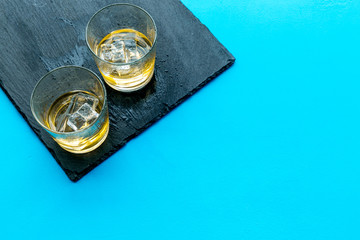 In the bar. Whiskey with ice on black desk on blue background top view copy space