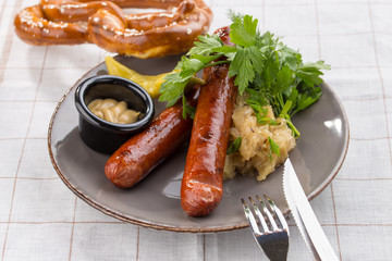 grilled sausages, served with beer, pretzels, pickles and mustard on the side for Octoberfest on textile background