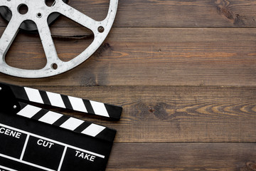 Filmings concept. Clapperboard and film stock on dark wooden background top view copy space