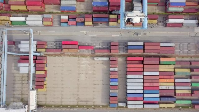 Transtainer yard - Various brands and colours of Shipping containers stacked by Transtainers (Mobile gantry cranes) off of service trucks - Top down aerial footage.