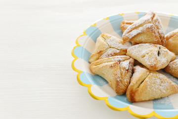 Purim celebration concept (jewish carnival holiday). Traditional hamantaschen cookies over white wooden table.