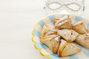 Purim celebration concept (jewish carnival holiday). Traditional hamantaschen cookies over white wooden table.