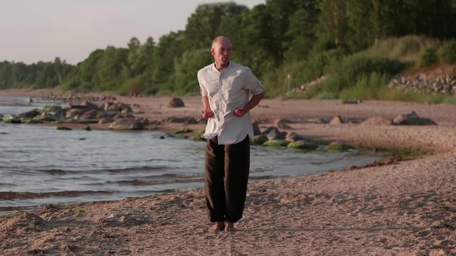 Martial artist monk practicing routine on the beach.