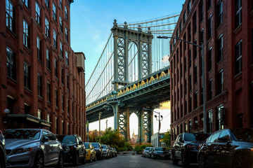 Manhattan bridge seen from a narrow alley enclosed by two brick buildings