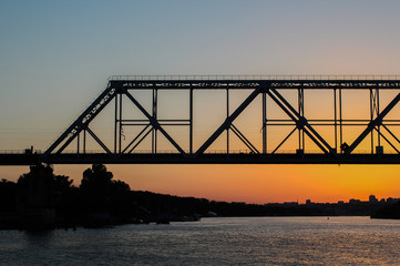 Fototapeta na wymiar Rails bridge on a sunset in the river