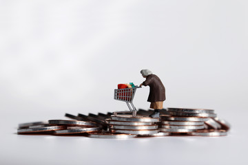 A miniature woman pulling a cart on a pile of coins.