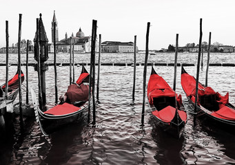 Blue old gondolas  docked at the pier the Piazza San Marco in Venice, Italy. Color in black and...