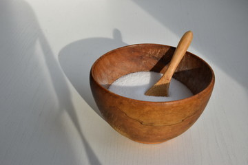 Wooden bowl with salt on the white table
